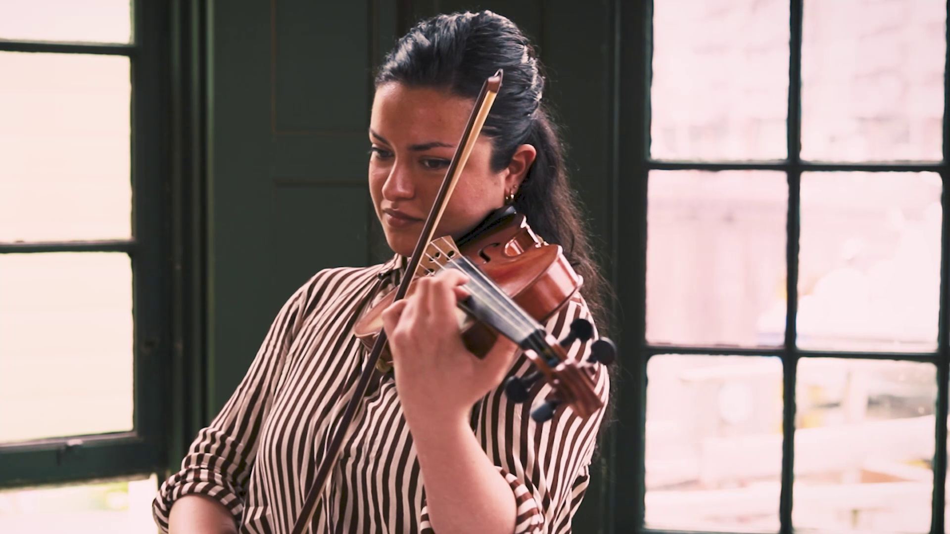 Violinist performing by the studio window